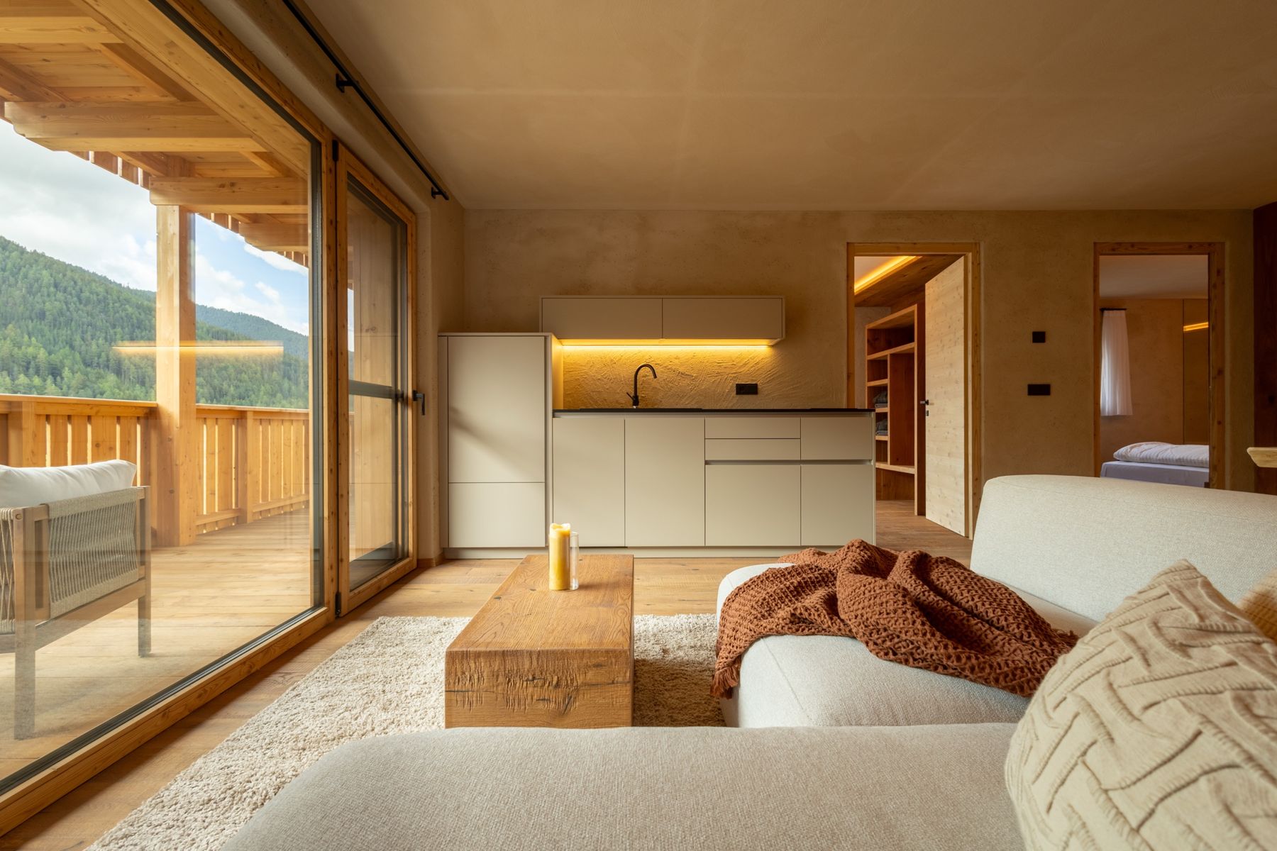 Heller Wohnraum mit Sofa, Holztisch und großer Glasfront zum Balkon
